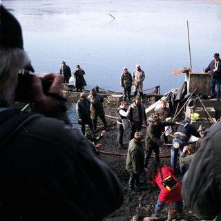 People gathered by a lake during a fishing event.