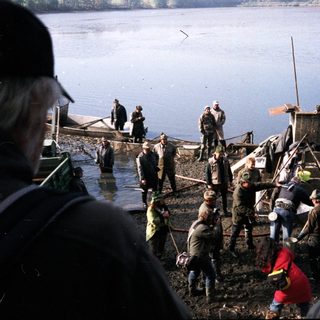 People fishing and working on a lake shore.