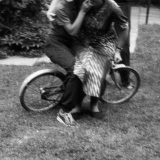 Two children joyfully hugging on a bicycle.