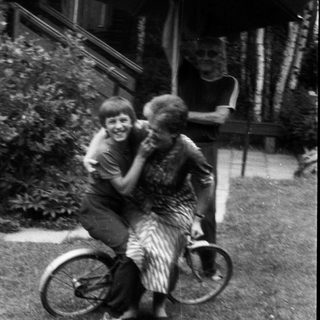 Two children joyfully hugging on a bicycle.