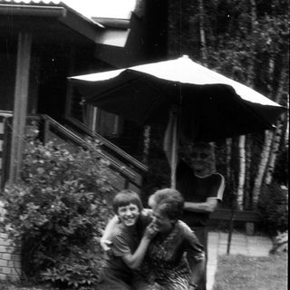 Two children joyfully hugging on a bicycle.