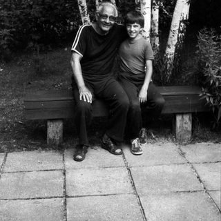 Two people sitting together on a bench outdoors.