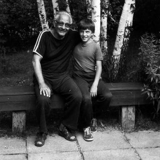 Two people sitting together on a bench outdoors.