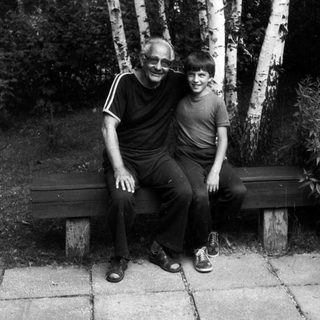 Two people sitting together on a bench outdoors.