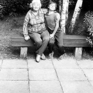 Two generations sitting together on a bench outdoors.