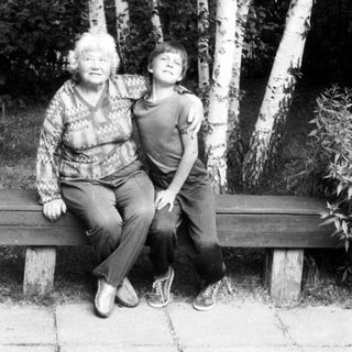 Two generations sitting together on a bench outdoors.