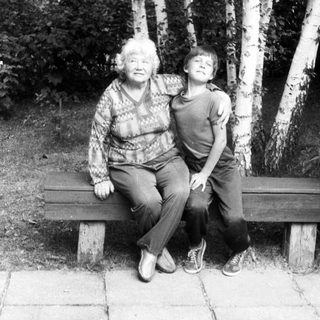 Two generations sitting together on a bench outdoors.