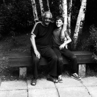 Two people sitting together on a bench outdoors.