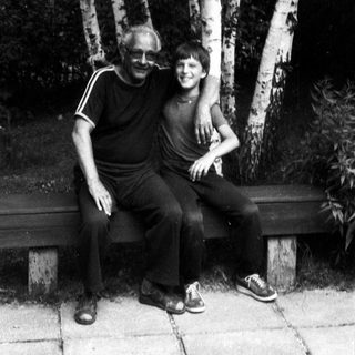 Two people sitting together on a bench outdoors.