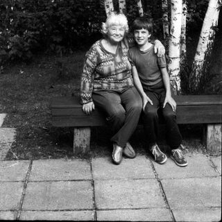 Two people sitting together on a bench in a birch forest.