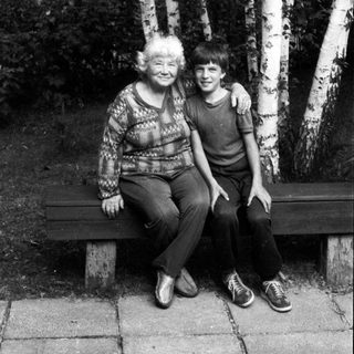 Two people sitting together on a bench in a birch forest.