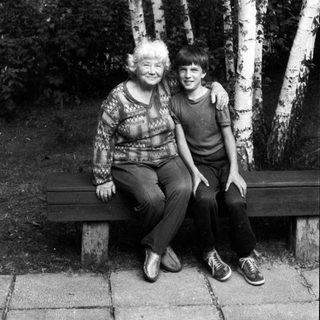 Two people sitting together on a bench in a birch forest.