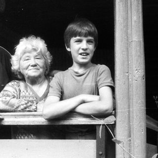 Family trio posing together on wooden balcony.