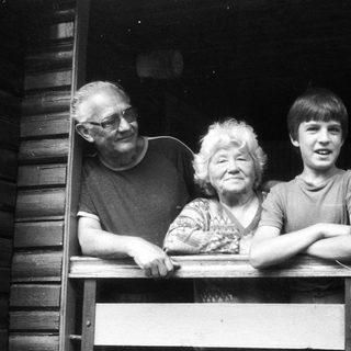 Family trio posing together on wooden balcony.
