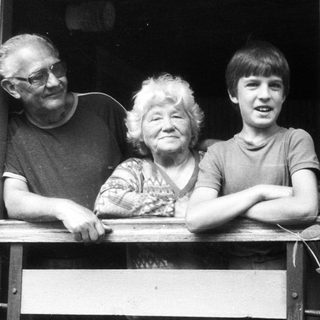 Family trio posing together on wooden balcony.