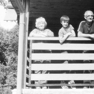Family posing on wooden porch steps.