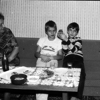 Two boys sitting at a table eating indoors.