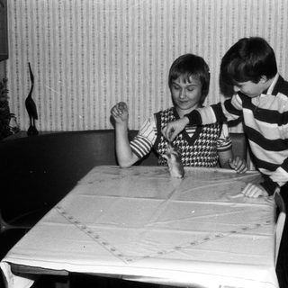 Two children playing board game indoors.