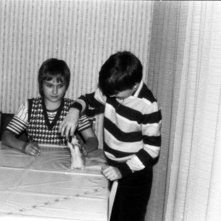 Two boys playing with a toy train indoors.