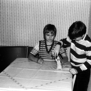 Two boys playing with a toy train indoors.
