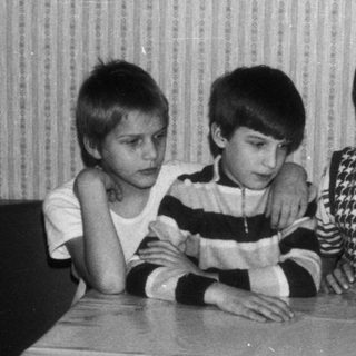 Three children sitting together at a table indoors.
