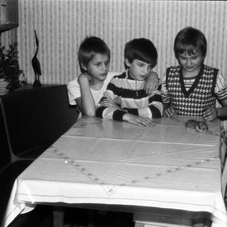 Three children sitting together at a table indoors.