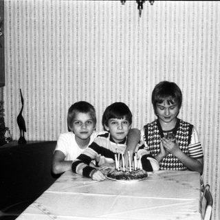 Three children posing with birthday cake.