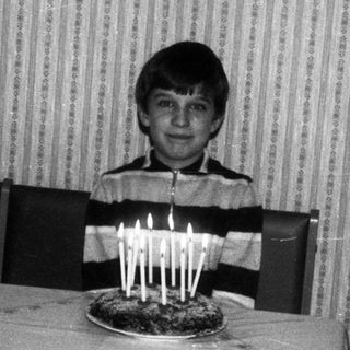 Young boy blowing out birthday candles on cake.