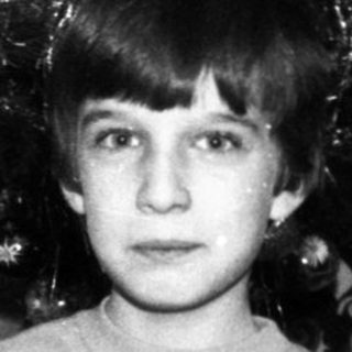 Young boy holding Christmas gift card indoors.