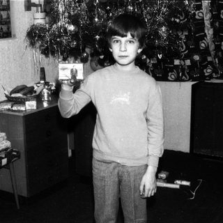 Young boy holding Christmas gift card indoors.