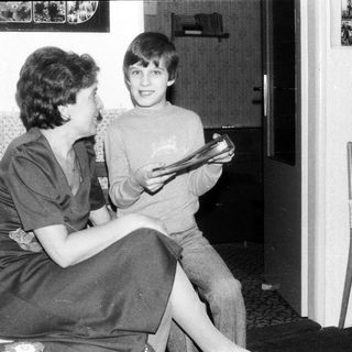 Two people reading together indoors, likely in a living room.