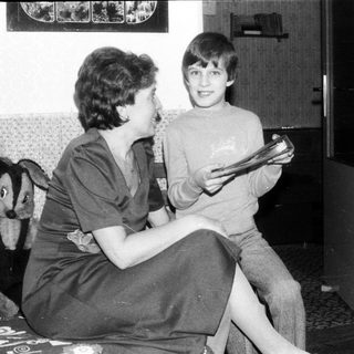 Two people reading together indoors, likely in a living room.