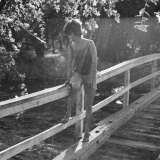A person standing on a wooden bridge in sunlight.