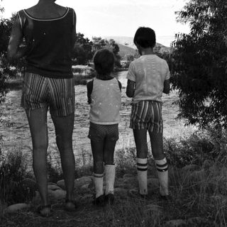 Family standing by riverbank in natural setting.