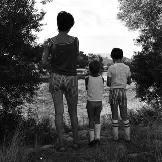 Family standing by riverbank in natural setting.
