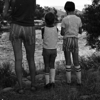 Family standing by riverbank in natural setting.