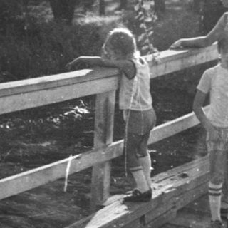 Two children walking on a wooden boardwalk in sunlight.