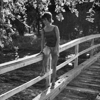 Person standing on a wooden bridge by water.