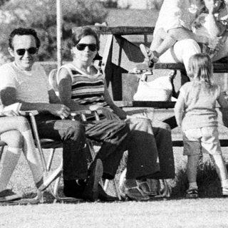 Group of people relaxing outdoors in 1970s-style clothing.