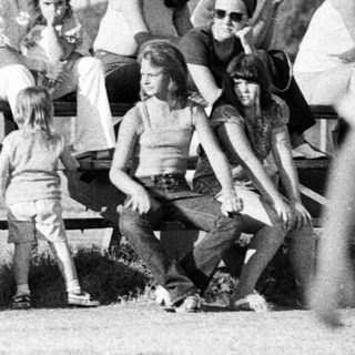 Group of people relaxing outdoors in 1970s-style clothing.
