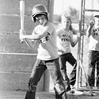 Two boys playing tee-ball in 1970s-style attire.