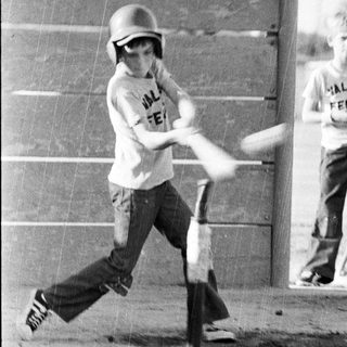 Young boy swinging baseball bat at tee stand.