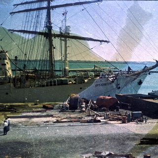 Historic shipyard with damaged ships and industrial equipment.
