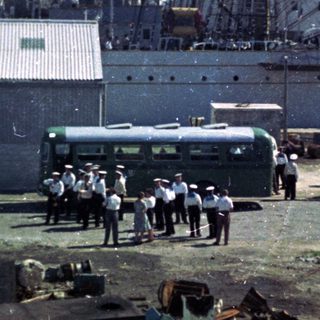 Port scene with shipwreck debris and workers inspecting damage.