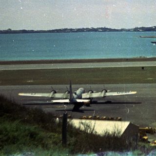 Airport runway by coastal waterfront with planes.