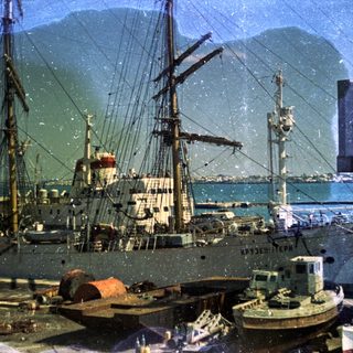Historic port scene with vintage ships and industrial harbor.