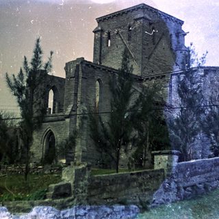 Ruined medieval stone church with tall tower.