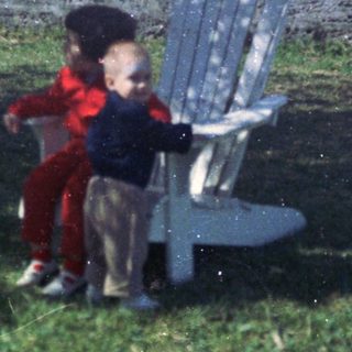 Two children playing near a bench outdoors.