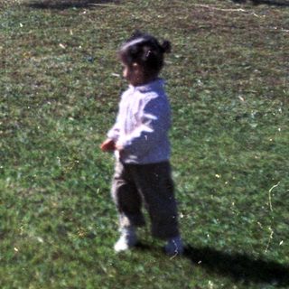 Child playing with fallen cow in grassy yard.
