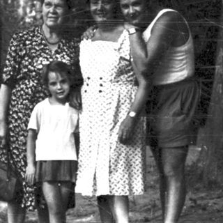 Family posing outdoors in wooded area.